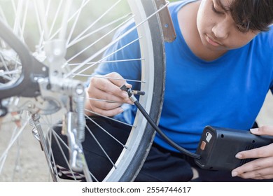 Asian child in blue t-shirt holding front tire or wheel and checking it before riding in front of his backyard, soft focus. - Powered by Shutterstock