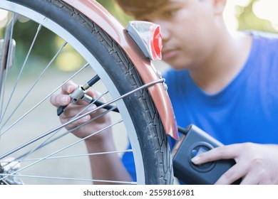 Asian child in blue t-shirt holding front tire or wheel and checking it before riding in front of his backyard, soft focus. - Powered by Shutterstock