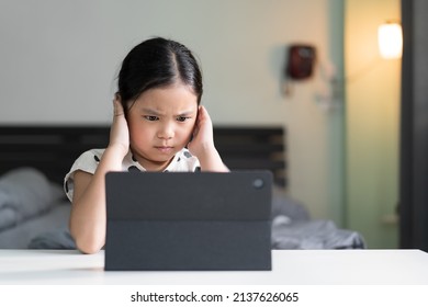 Asian Child Bored Covering Or Close Ears In Studying Online Class Or Kid Girl Student Back To School To Angry Stressed Learning On Computer Tablet By Video Call Or Person Learn From Home For Education