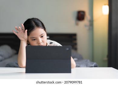 Asian Child Bored Headache In Studying Online Class Or Kid Girl Student Back To School To Stressed Learning On Computer Tablet By Video Call Or Person Learn From Home On Pad For Education In Bedroom