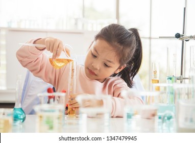 Asian child chemist holding flask and test tube in hands in lab learning chemistry experiment. Scientist chemistry and science education concept.
