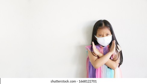 Asian Child Cross Arm Or Kid Girl Strong Wear N95 Paper Face Mask For Close Mouth Nose And Fight Sick With Cold Cough And Protect PM2.5 Dust Or Influenza Virus And Bacteria From Smoke On White Space