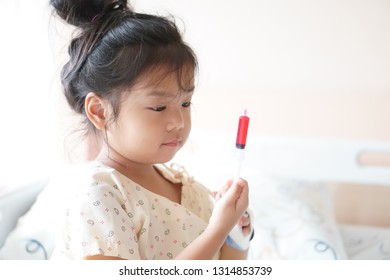 Asian Child Cute Or Kid Girl Influenza Sick Holding And Eating Or Taking Sweet Red Drug Or Water Medicine By Syringe Pump On Bed At Hospital Room For Pediatric Patient Treatment And Healthcare