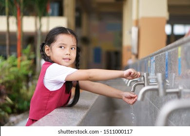 Asian child cute or kid girl and student smiling happy with wash hands on tap in sink on public at kindergarten school or preschool for dirty clean and bacteria or virus with wear school uniform - Powered by Shutterstock