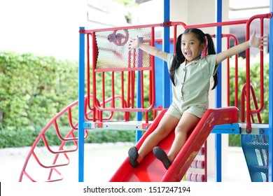 Asian child cute or kid girl smiling playing slider and happy fun or cheerful enjoy with extend arms on holiday relax exercise at playground public park in kids club or nursery kindergarten and school