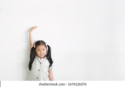 Asian Child Cute Or Kid Girl Happy Smiling Show Height Or High And Measure Tall With 6 Years Growth By Hand And Arm Up From Milk Drink And Protein On Empty White Wall Background Isolated With Space