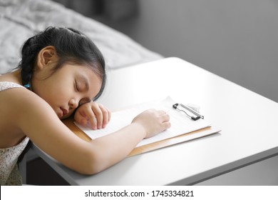 asian child cute kid girl writing draw   doing homework learn   training write paper but fall asleep sleep rest table by stay home   kindergarten study online in gray bedroom