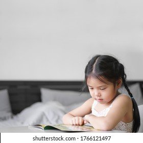 Asian Child Cute Or Kid Girl Happy And Student Enjoy Reading Story Book Or Cartoon And Smile By Learn From Home To Read Study With Education On Table In Bedroom Or Nursery Kindergarten Back To School