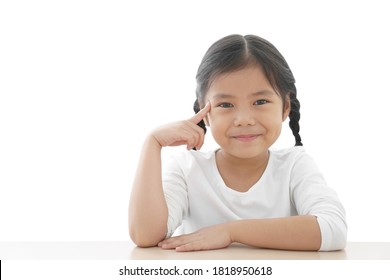 Asian Child Cute Or Kid Girl Finger Point Brain Head For New Idea Think And Imagination Or Creativity Education With Smiling Happy At Nursery Pre School On Table And White Space Background Isolated