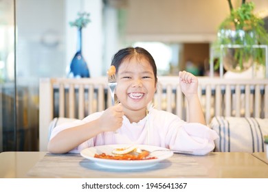 Asian Child Cute Or Kid Girl Smile Laugh Holding Fork To Enjoy Eating Sausage And Fried Egg With Grilled Bacon To Morning Food And Hungry On White Dish With Happy For Breakfast At Kitchen Restaurant