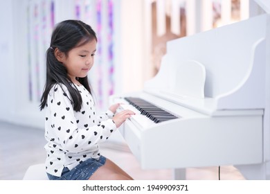 Asian Child Cute Or Kid Girl Musician Smile And Happy Playing White Piano Or Electone To Song Show On Stage Or People Learn At Music School For Artist Education