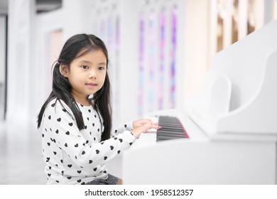 Asian Child Cute Or Kid Girl Musician Smile And Happy Playing White Piano Or Electone To Song Show On Stage Or People Learn At Music School For Artist Education