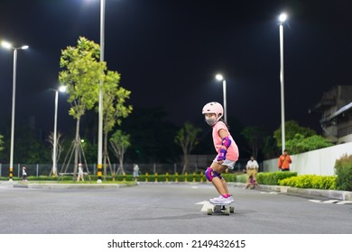 asian child exercise or kid girl playing skateboard or surf skate in skating rink or extreme sports park at night to wearing face mask helmet elbow pads wrist and knee support for body safety protect - Powered by Shutterstock