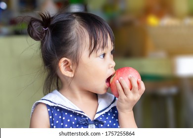 Portrait​ Image​ Of​ 2-3​ Yeas​ Old​ Of​ Baby.​ Happy​ Asian Child Girl Eating And Biting A​ Red Apple. Enjoy Eating Moment. Healthy Food And Kid Concept.​