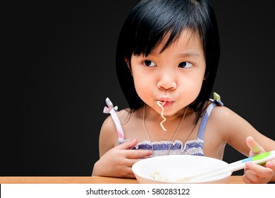 Asian Child Girl Eating Instant Noodles Isolated On Black Background, With Clipping Path