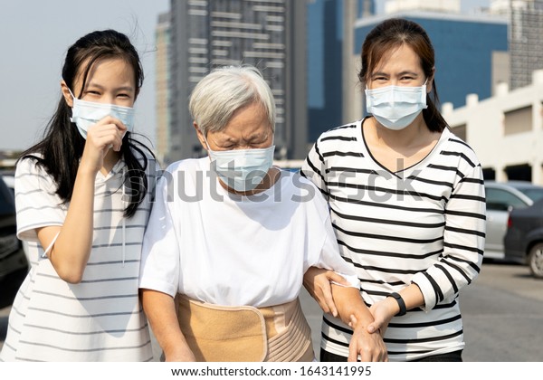 Asian child girl and family suffer from allergic\
rhinitis,cough,sneeze wearing protection mask in city,sick woman\
with medical mask to prevent air pollution,fine dust,smog,illness\
from dust allergy