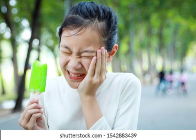 Asian Child Girl Holding Her Hand On Her Aching Tooth Have Hypersensitive Teeth Eating Ice-cream,feel Painful,female Teenage Have Sensitive Teeth Problem With Ice-lolly,tooth Decay,dental Care Concept