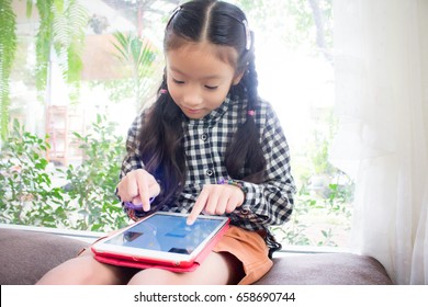 Asian Child Girl Look Smart Phone.kid Is Playing On Ipad 