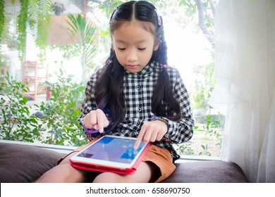 Asian Child Girl Look Smart Phone.kid Is Playing On Ipad 