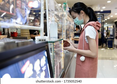 Asian Child Girl In A Mask,buying Food At Shopping Mall After Coronavirus Quarantine Covid-19,restaurant Has Plastic Shield Partition And Hand Sanitizer In Front Of The Shop,safety,social Distancing