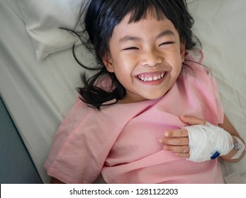 Asian Child Girl On Hospital 's Bed With Positive Mood. Big Smiling On Bed.