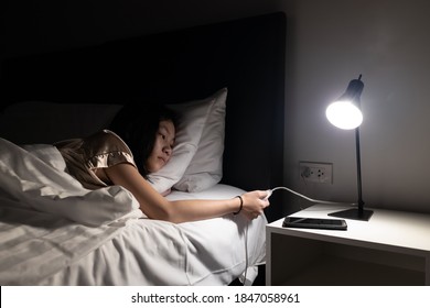 Asian child girl resting on the bed,turning off the light switch before bedtime to sleep in the bedroom at night,turn off lights when not in use,hand turning off lamp,energy power saving , save money - Shutterstock ID 1847058961