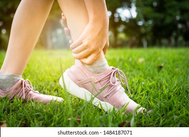 Asian Child Girl Touching Painful Twisted Or Broken Ankle,female Sport Running Ankle Sprain,legs Have Problem,accident,woman Hand Massaging Her Leg Pain,feel Ache Injury After Exercise In Outdoor Park