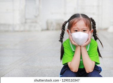 Asian Child Girl Wearing A Protection Mask Against PM 2.5 Air Pollution With Pointing Up In Bangkok City. Thailand.
