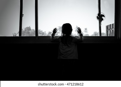 Asian Child Girls Are Standing In The Dark, Looking Out The Window,sad Mood, Black And White Tones.