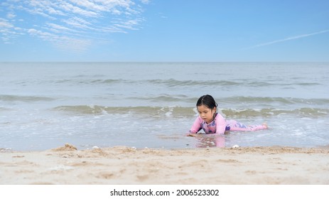 Asian Child Happy Or Kid Girl Lying Down Alone On Beach To Sleep Playing Sand On Blue Sea And Sky On Morning Daytlight Or Evening For Vacation Travel Trip On Summer Holiday Relax And Wearing Swimsuit