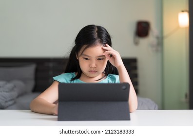 asian child headache on studying online class or kid girl student thinking or stressed learning on computer tablet by video call or person learn from home school and hand raising or holding to head