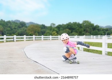 Asian Child Or Kid Girl Enjoy Playing Skateboard Or Surf Skate In Skatepark Track To Extreme Sports Exercise By Crouching Turn Or Person Smile Wearing Helmet Elbow Knee Support For Body Safety Protect