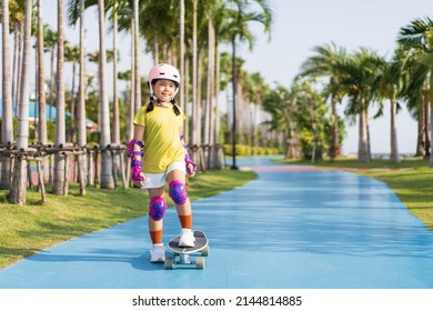 asian child or kid girl playing skateboard or surf skate in skating rink track and extreme sports exercise to wearing helmet elbow pads wrist and knee support for body safety protect at bang phra park