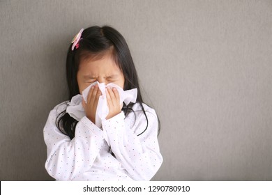 Asian Child Or Kid Girl Sick With Sneezing On Nose And Cold Cough On Tissue Paper Because Weak Or Virus And Bacteria From Dust Weather And Kindergarten And Pre School For Medical Background Gray Space