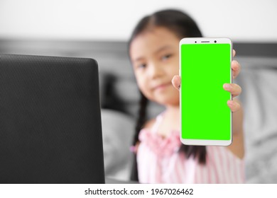 Asian Child Or Kid Girl Smile Hold Smartphone Or Mobile Phone For Show Present Empty Green Screen Display To Learn Or Study Online And Work At Home On Computer With Clipping Path On Smartphone Display