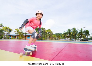 asian child or kid girl smile playing skateboard or surf skate to fun turn in skatepark and extreme sports exercise to wearing helmet elbow pad wrist and knee support for body safety at bang phra park - Shutterstock ID 2174634741