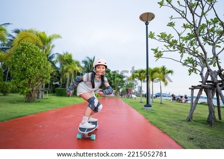asian child or kid girl smile playing skateboard or riding surf skate carving and fun in skate park for extreme sports exercise to wearing helmet elbow wrist knee support for body safety at bang phra