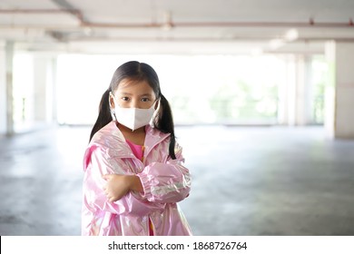 Asian Child Or Kid Girl Wearing N95 White Face Mask And Coat Sweater To Close Mouth Nose With Flu Cough Sick And Protect PM 2.5 Dust Or Covid-19 Coronavirus To Arms Folded On Cold And Winter Season