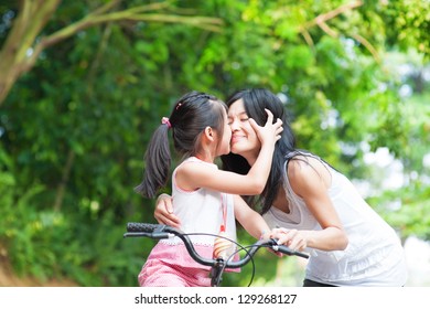 Asian Child Kissing Her Mother. Asian Family Having Fun Outdoor, Biking Outdoor.