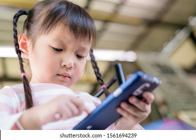 Asian child little girl playing game or watching video on mobile phone. Concept smartphone addiction to short attention span can have negative effects, including: poor performance at life or school