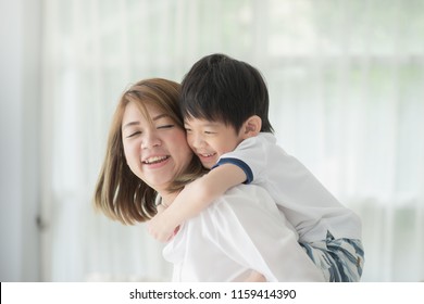 Asian Child On A Piggy Back Ride With His Mother At Home