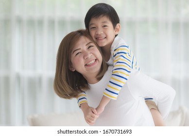 Asian Child On A Piggy Back Ride With His Mother At Home