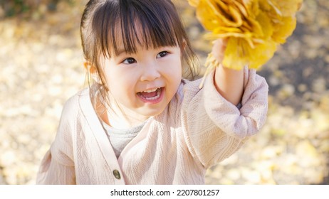 Asian child picking up fallen leaves