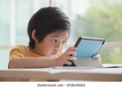 Asian Child Playing Game On Tablet With Serious Face