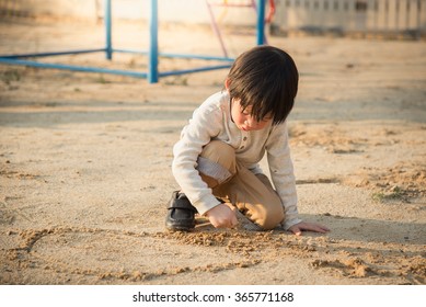 Asian Child Playing With Sand In The Playground