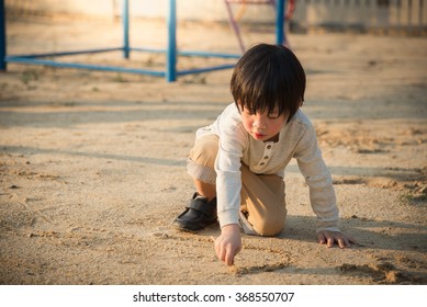 Asian Child Playing With Sand In The Playground