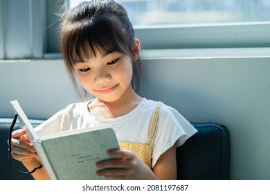 Asian child reading book at home - Shutterstock ID 2081197687