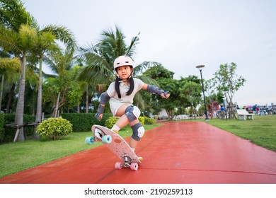 asian child skater or kid girl playing skateboard or surf skate and ollie jumping fun or raise wheel manual in skate park by extreme sports to wear helmet elbow pads wrist knee support for body safety - Shutterstock ID 2190259113