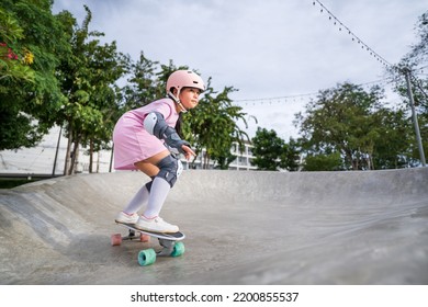 asian child skater or kid girl playing skateboard or ride surf skate and fun in wave bank or wave ramp to carving surfing in skatepark by extreme sports to wearing helmet knee support for body safety
