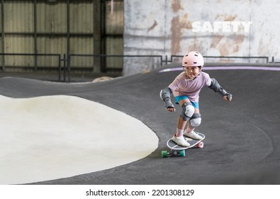 asian child skater or kid girl fun playing skateboard or ride surf skate and turn on pump track in skate park by extreme sports to wearing helmet elbow pads wrist knee support for body safety protect - Shutterstock ID 2201308129